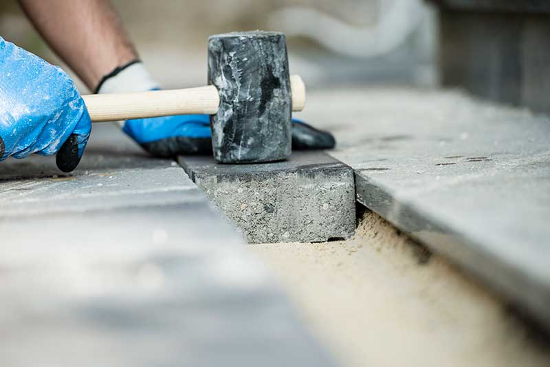 builder laying paving stone brick