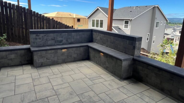 Paver Patio and Seat Wall in Beaverton, OR: A Level Patio Built Into the Slope Under a Deck, With a Seat Couch and Lit Side Yard Steps